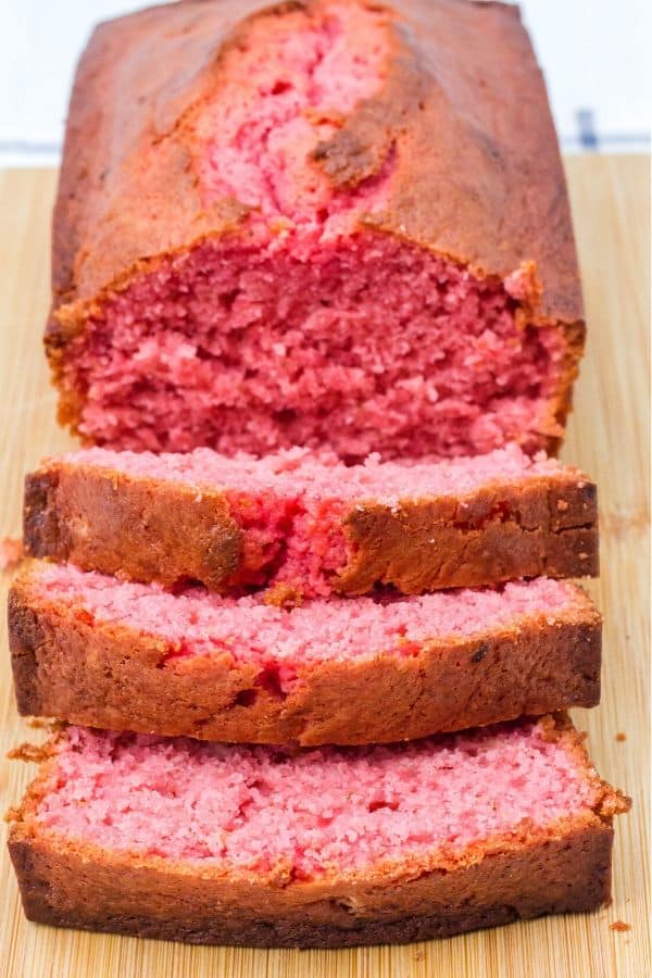 A loaf of banana strawberry bread on a cutting board for slicing