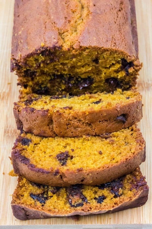 overhead view of a loaf of pumpkin chocolate chip bread on a cutting board, which has been sliced