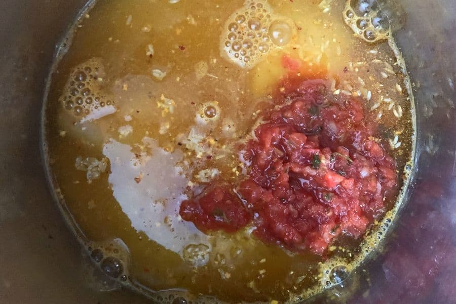 ingredients for arroz con pollo, including water, salsa, chicken, and Spanish rice, in the insert pot of the Instant Pot