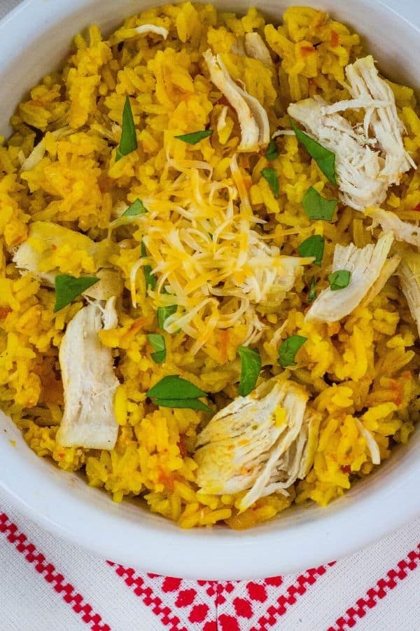 Bowl of pressure cooker arroz con pollo topped with shredded cheese and chopped cilantro