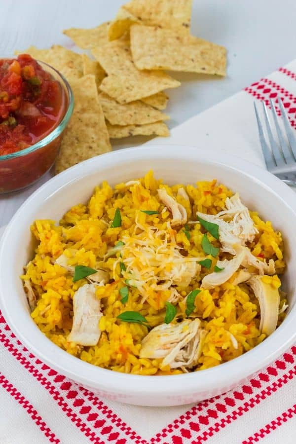 arroz con pollo that was cooked in the Instant Pot, served in a white bowl along with tortilla chips and salsa