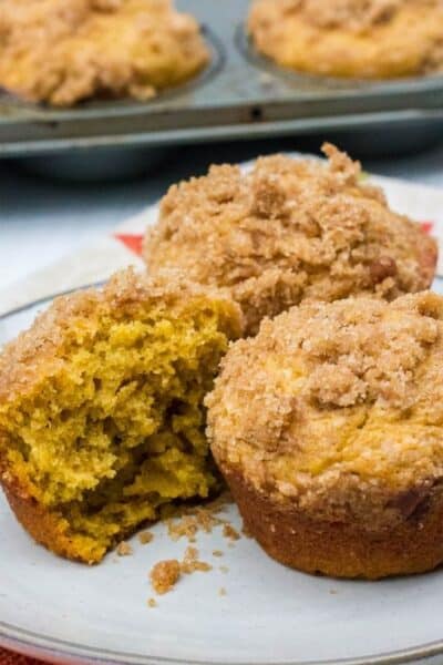 pumpkin banana muffins on a white plate, with one of the muffins cut in half