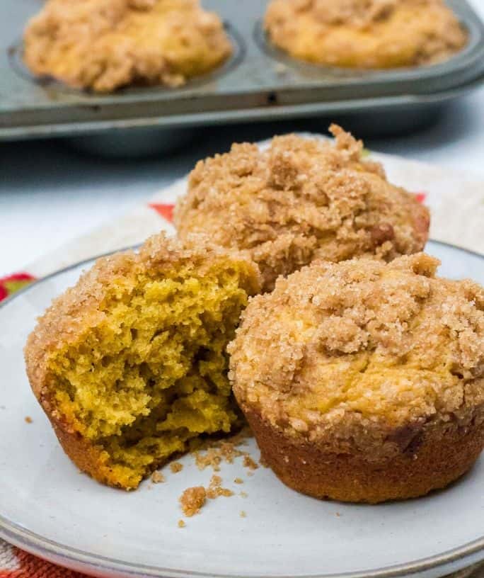 pumpkin banana muffins on a white plate, with one of the muffins cut in half