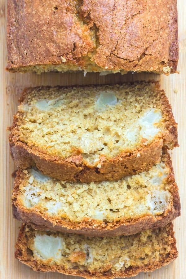 a loaf of pear bread that has been partially sliced, with slices laying open