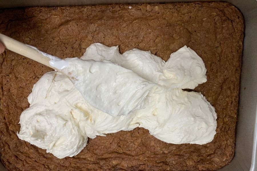 spreading frosting on the oatmeal cream pie cookie base