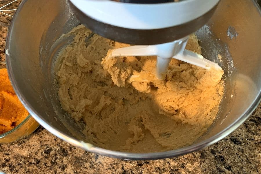 an electric mixer beating butter and sugars and pumpkin puree together for pumpkin oatmeal cookies
