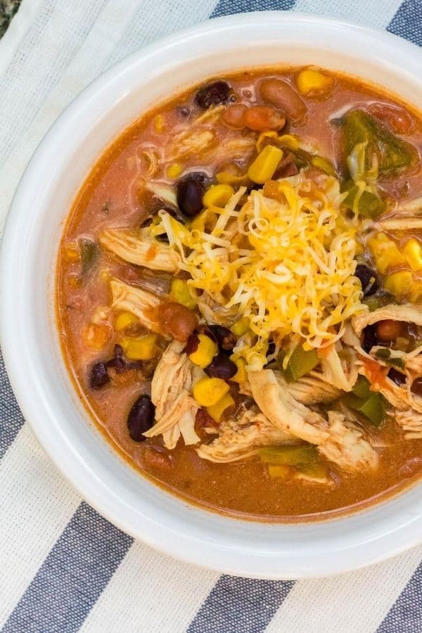 Instant Pot chicken taco soup in a white bowl, topped with shredded cheese