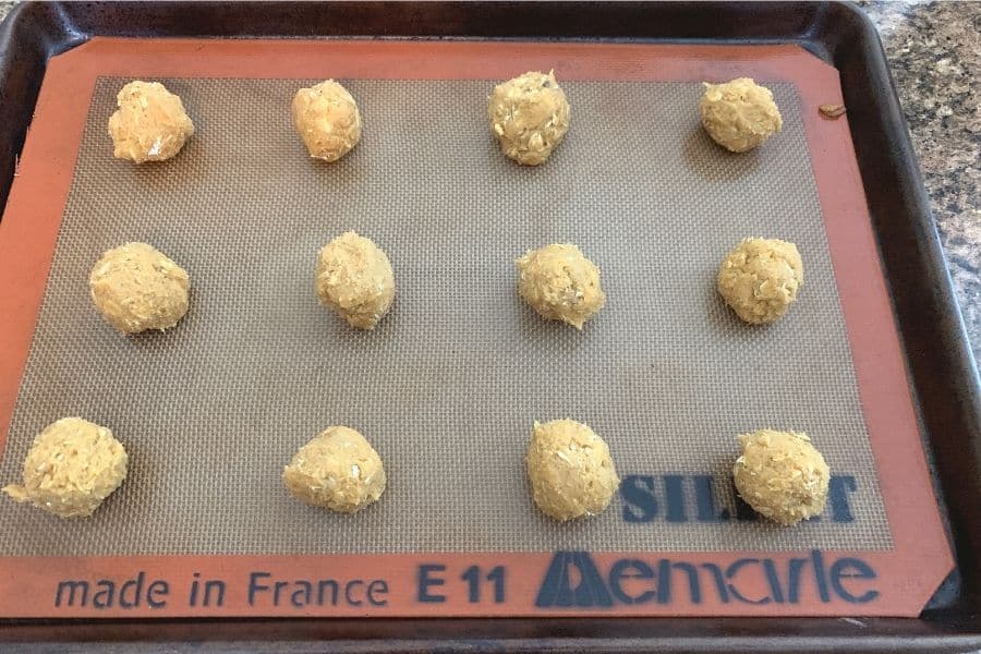 rounds of pumpkin oatmeal cookie dough on a baking sheet to be placed in the oven