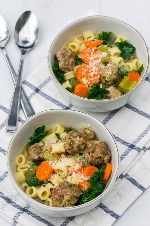 Two bowls of Instant Pot Italian wedding soup on a blue and white napkin
