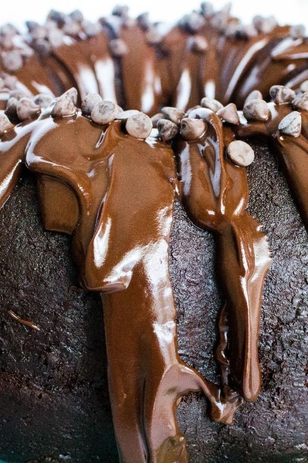 up-close view of a triple chocolate bundt cake made from a cake mix and pudding, then drizzled with satiny chocolate ganache on top and sprinkled with mini chocolate chips