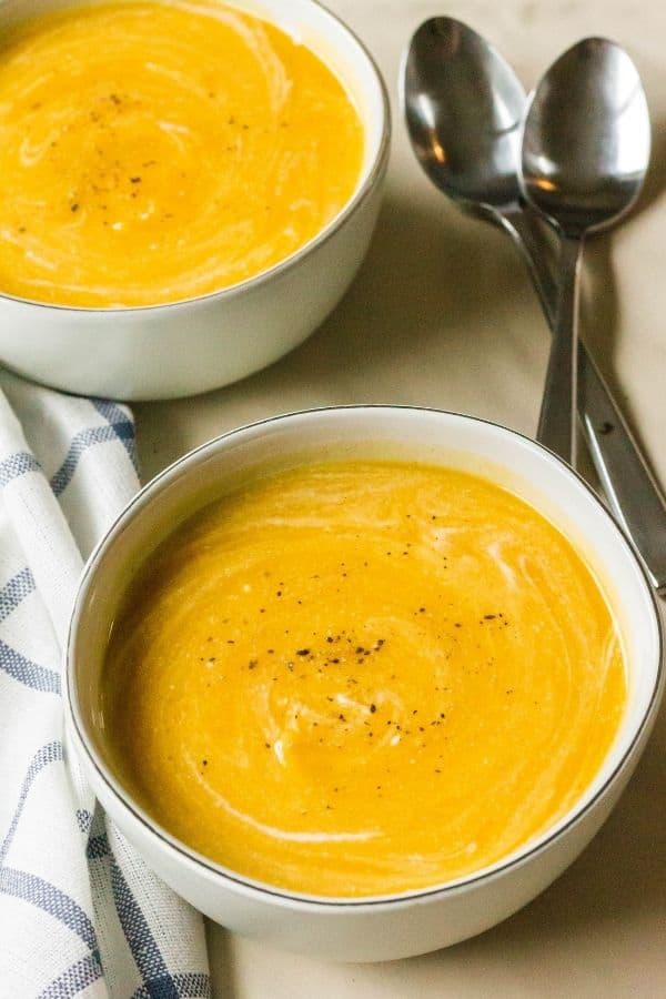 two bowls of pressure cooker butternut squash soup, with two spoons in the background