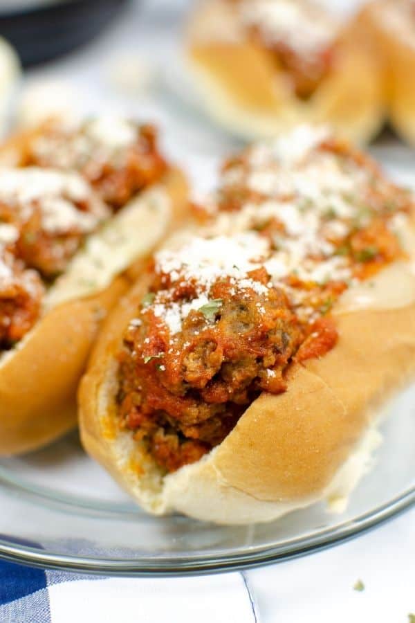 Close-up view of an Instant Pot meatball sub. Meatballs tossed in sauce are in a hoagie roll with provolone and parmesan cheese.