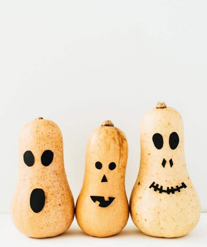 three white gourds with black faces on them