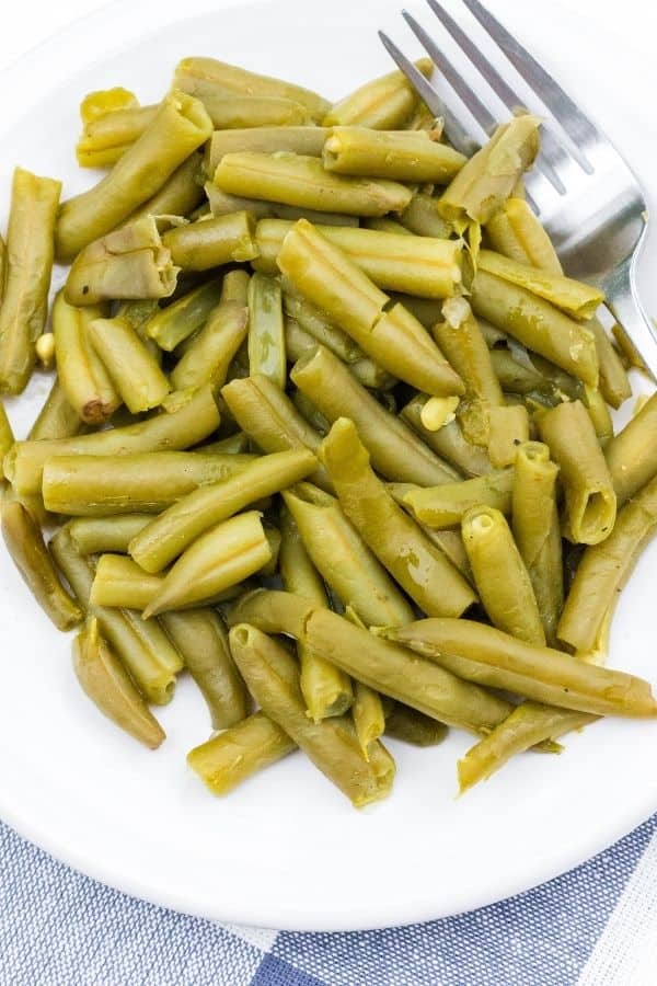 southern style canned green beans cooked in the Instant Pot, on a white plate with a fork in them