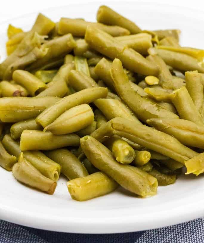 white plate piled with a helping of canned green beans cooked in the pressure cooker