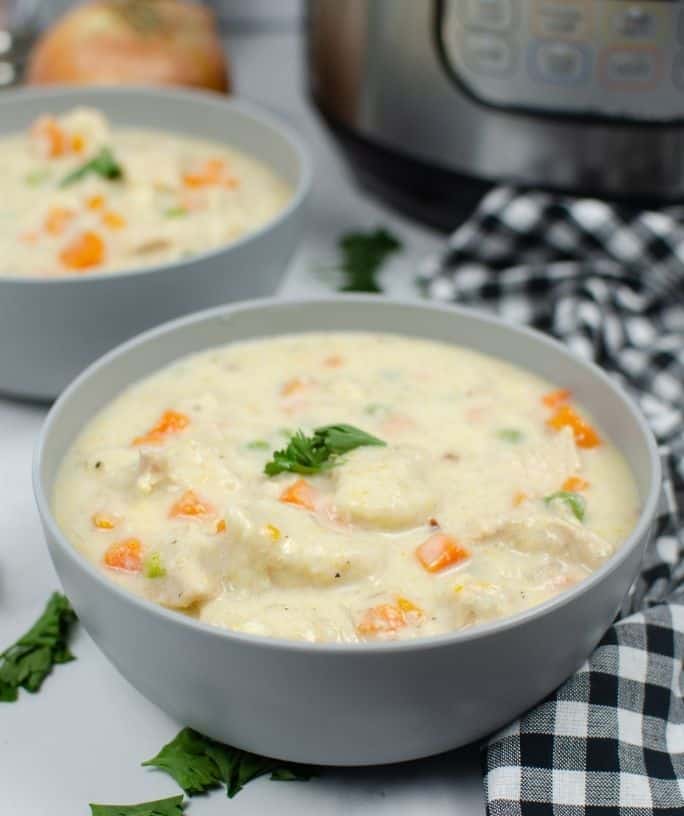two bowls of chicken and dumplings in front of an Instant Pot pressure cooker