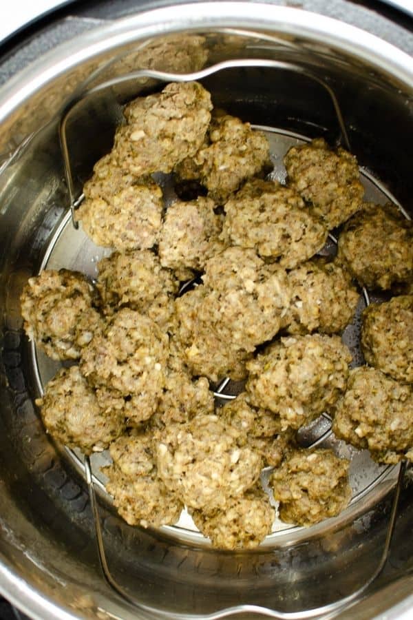 frozen meatballs that have been cooked in the Instant Pot, resting on the trivet in the insert pot, ready to be drained