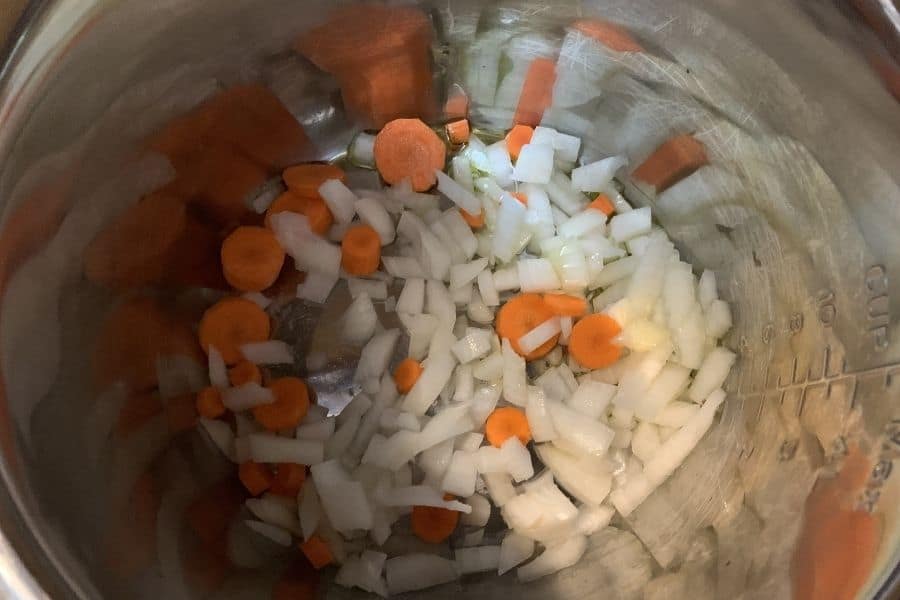 onions and carrots being sauteed in the Instant Pot for squash soup