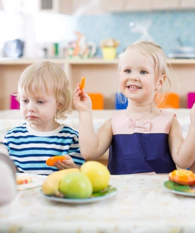 children sitting at a table with plates of food