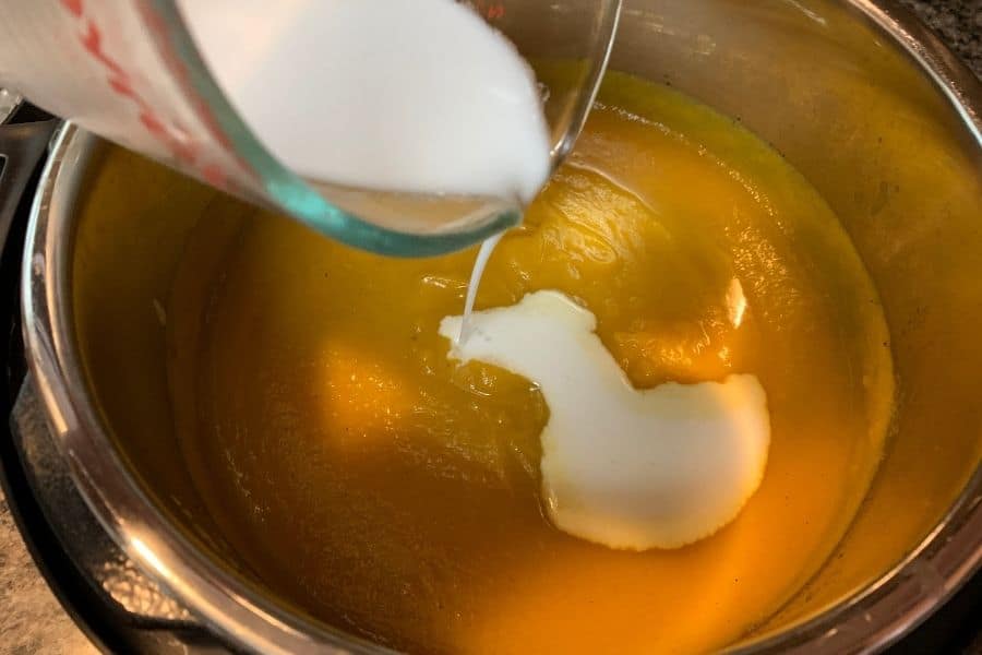 coconut milk being poured into the freshly blended Instant Pot butternut squash and apple soup