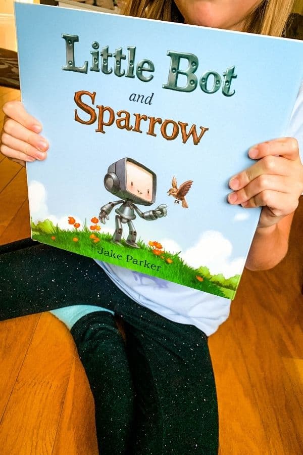 elementary aged girl holding a book titled "Little Bot and Sparrow."
