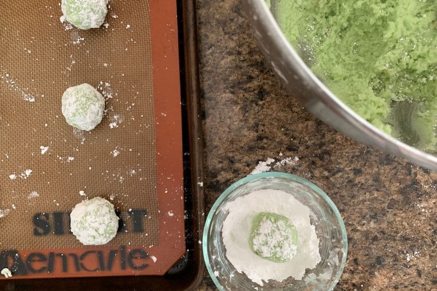 balls of pistachio cookie batter rolled in powdered sugar