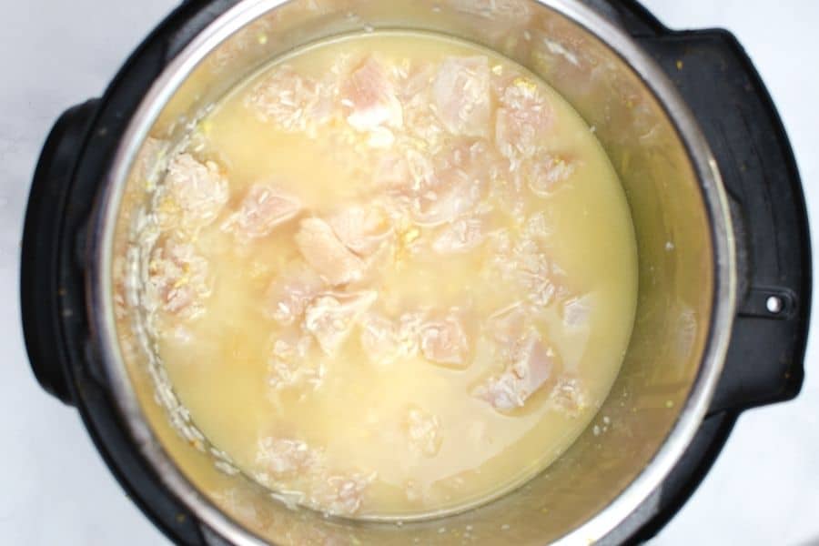 chicken, rice, broth, and seasonings in the insert pot of the Instant Pot, ready to be cooked for chicken fried rice.