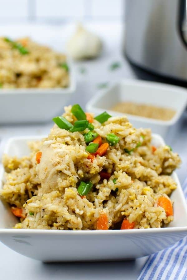 chicken fried rice cooked in the Instant Pot, piled into a white square bowl and topped with green onions