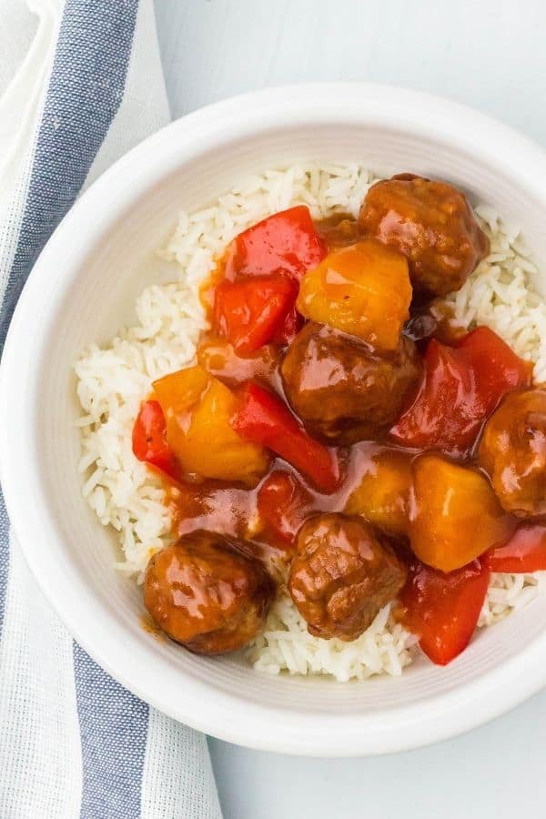 a white bowl filled with white rice and topped with Hawaiian meatballs cooked in the pressure cooker, along with pineapple and peppers