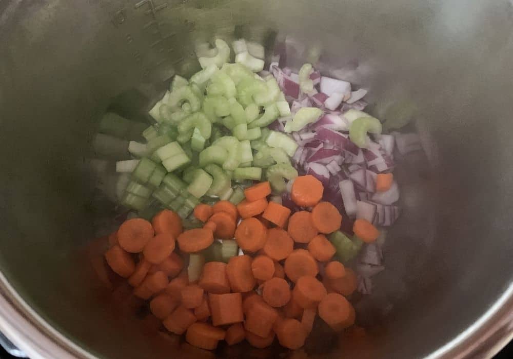 onions, carrots, and celery being Sauteed in the insert pot of the Instant Pot