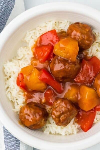 white bowl with a bed of white rice topped with Instant Pot Hawaiian meatballs, pineapple, and peppers