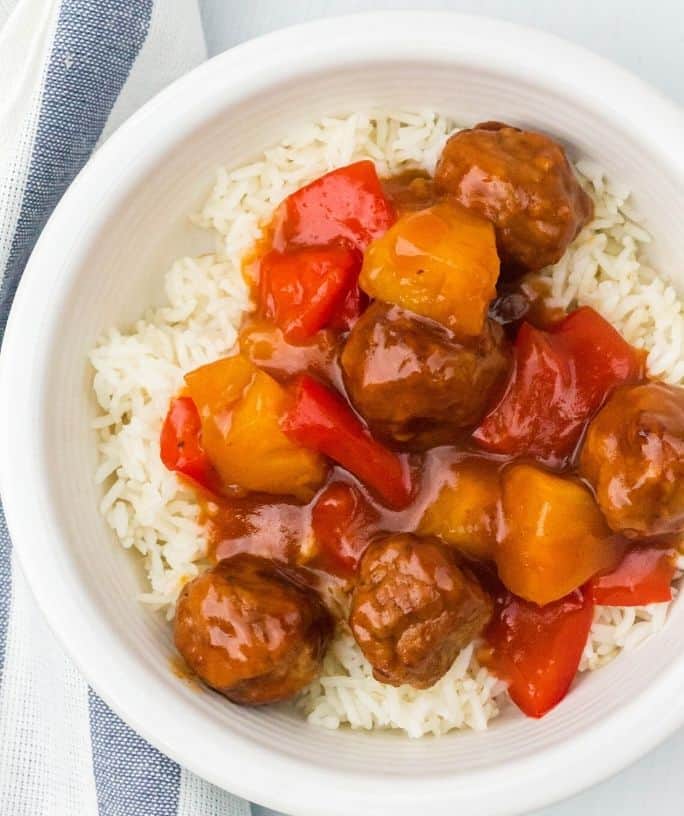 white bowl with a bed of white rice topped with Instant Pot Hawaiian meatballs, pineapple, and peppers