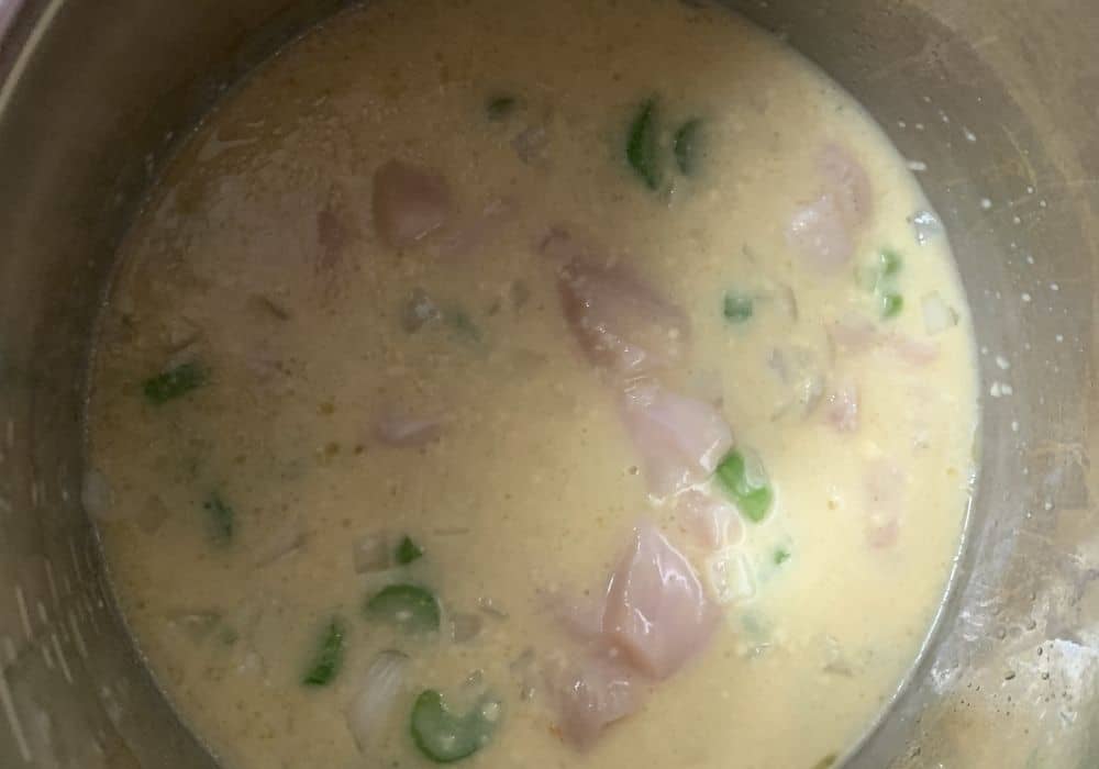 chicken broth, cream of chicken soup, chicken, celery, and onions mixed together in the Instant Pot for making pressure cooker chicken and dressing