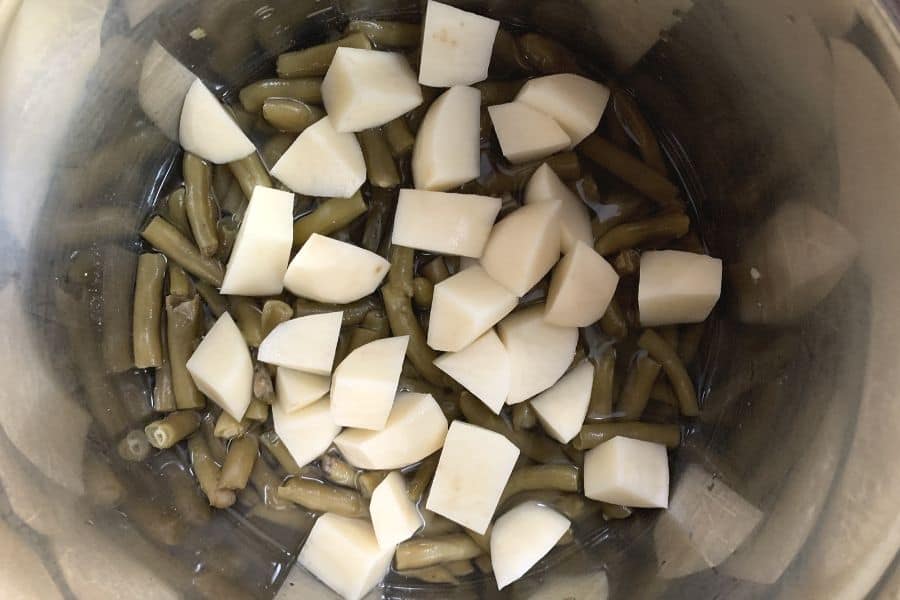 canned green beans and fresh potatoes in the Instant Pot, ready to undergo pressure cooking