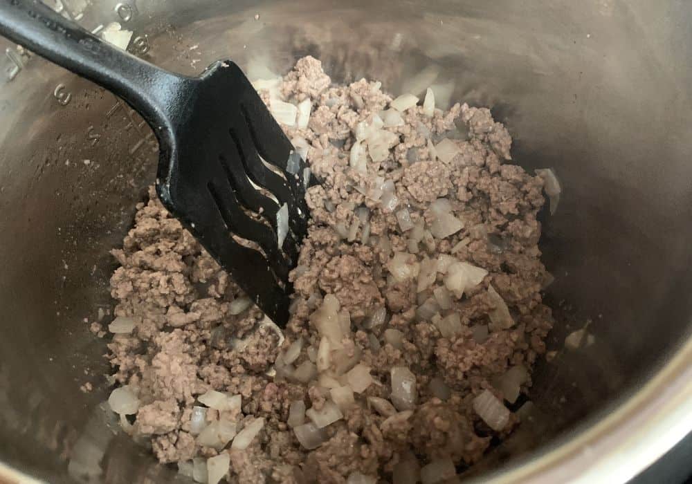 ground beef and onions in the insert pot of the Instant Pot for making pasta e fagioli