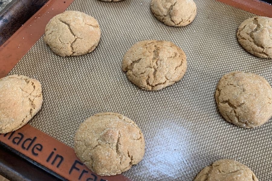 Freshly baked molasses cookies on a baking sheet.