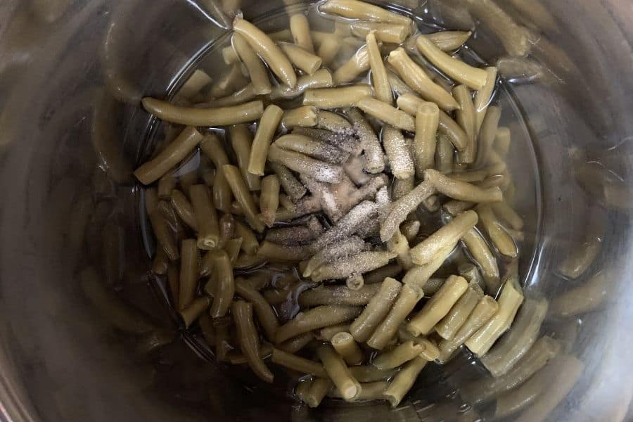 an Instant Pot containing canned green beans with seasonings on top