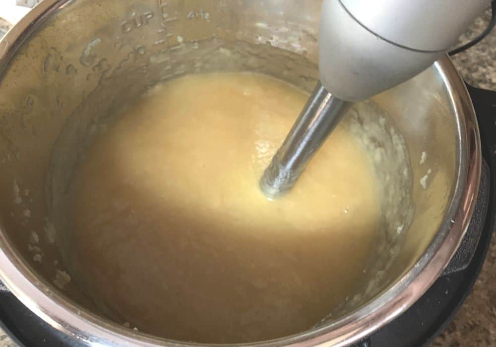 an immersion blender pureeing the apples into applesauce in the Instant Pot
