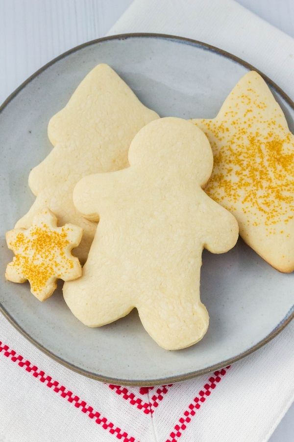 a beige stoneware plate with several Bisquick sugar cookies on it; some are plain and some have gold sprinkles on them.