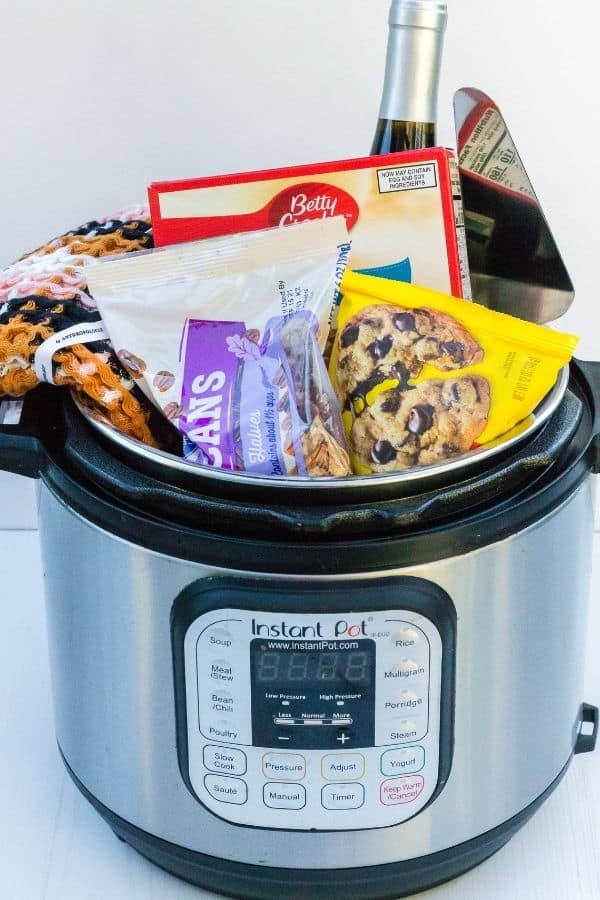 Dessert-themed Instant Pot gift basket filled with chocolate, pecans, cake mix, wine, hand towel, and dessert server