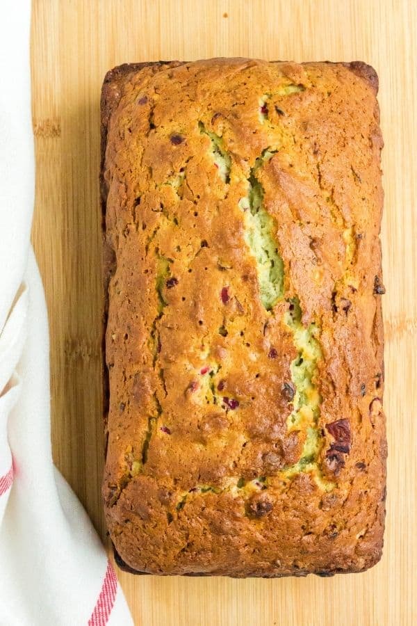 loaf of holiday pistachio cranberry bread on a cutting board