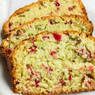 three slices of cranberry pistachio bread on a white plate for serving