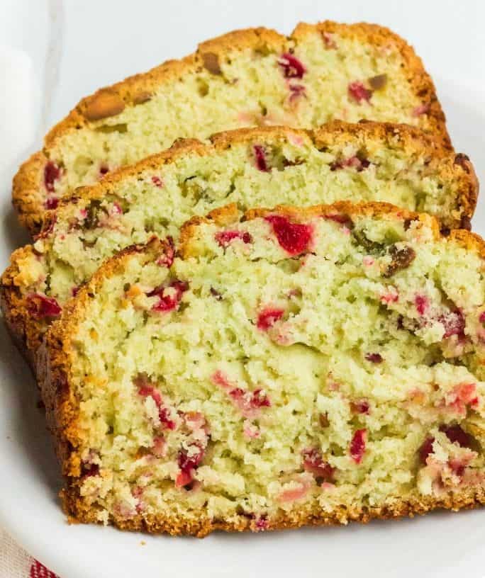 three slices of cranberry pistachio bread on a white plate for serving