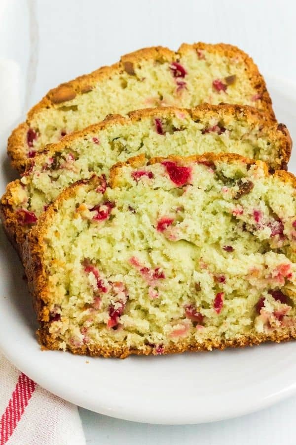 three slices of pistachio nut bread with cranberries, made from scratch and served on a white plate
