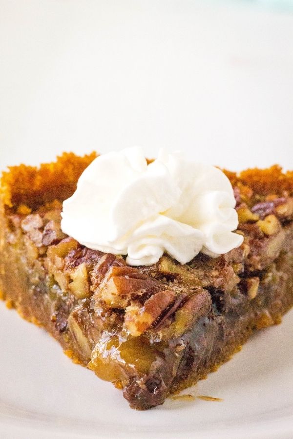 a head-on view of a slice of pressure cooker pecan pie with a dollop of whipped cream on top