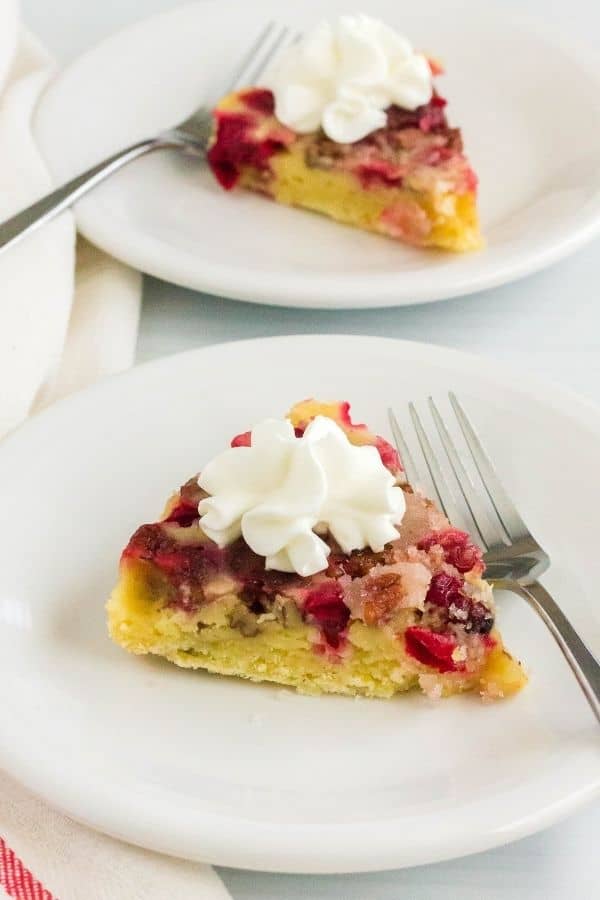 two white plates, each serving a slice of Instant Pot cranberry pie topped with whipped cream, with forks next to each slice