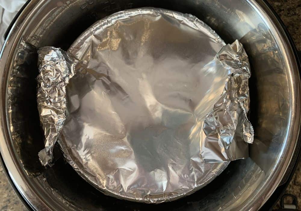 pecan pie in the insert pot of the Instant Pot, covered with foil for cooking.