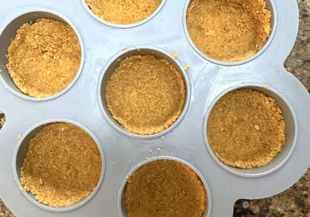 graham cracker crusts pressed into the wells of an egg bites mold for making Instant Pot cheesecake bites