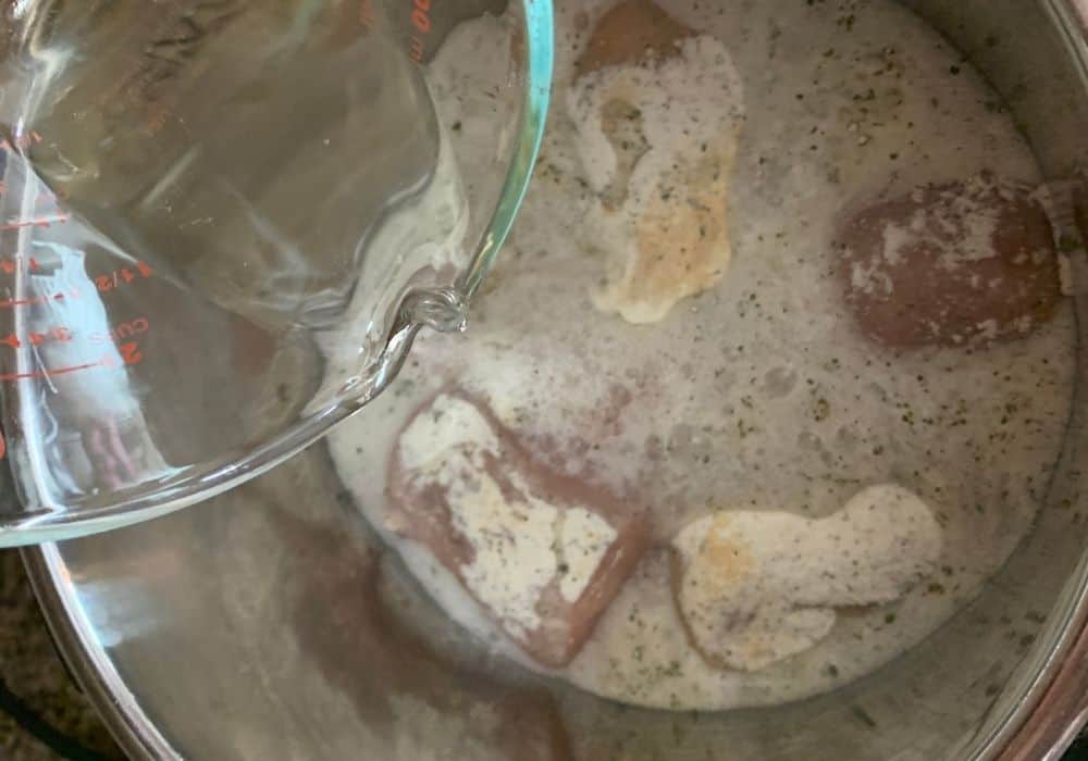 Ginger ale being poured over chicken seasoned with ranch packets in the Instant Pot