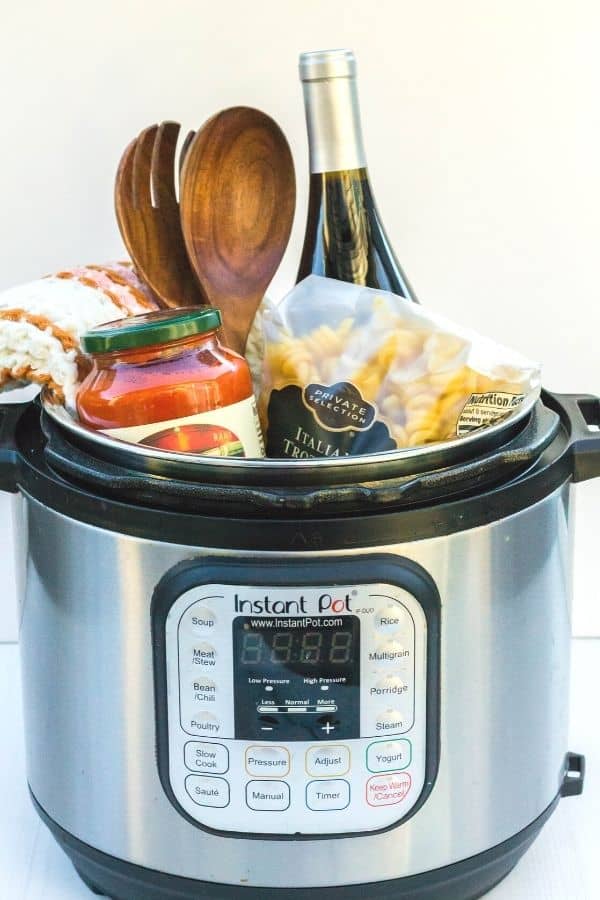 Italian-themed Instant Pot gift basket filled with wine, utensils, pasta sauce, and pasta.